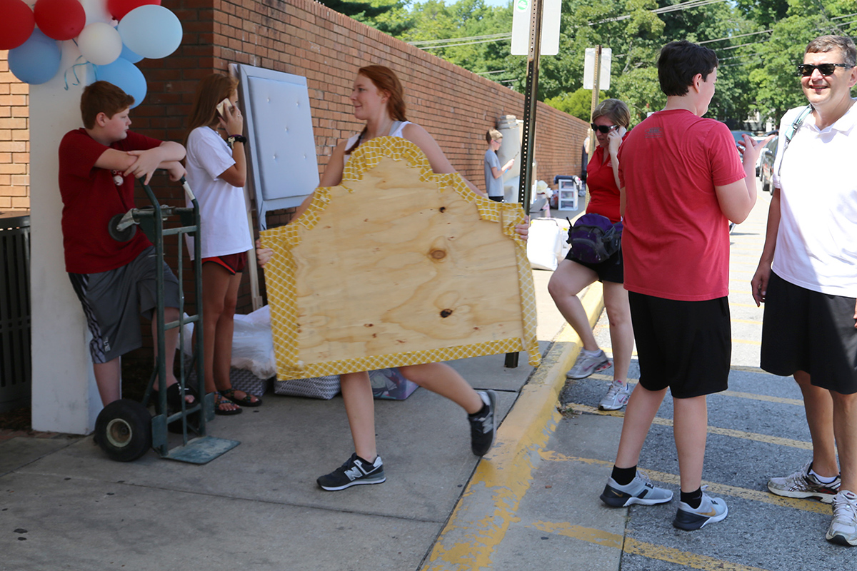 A Gamma Chi carries a headboard into Reid where it will soon become part of the decor.